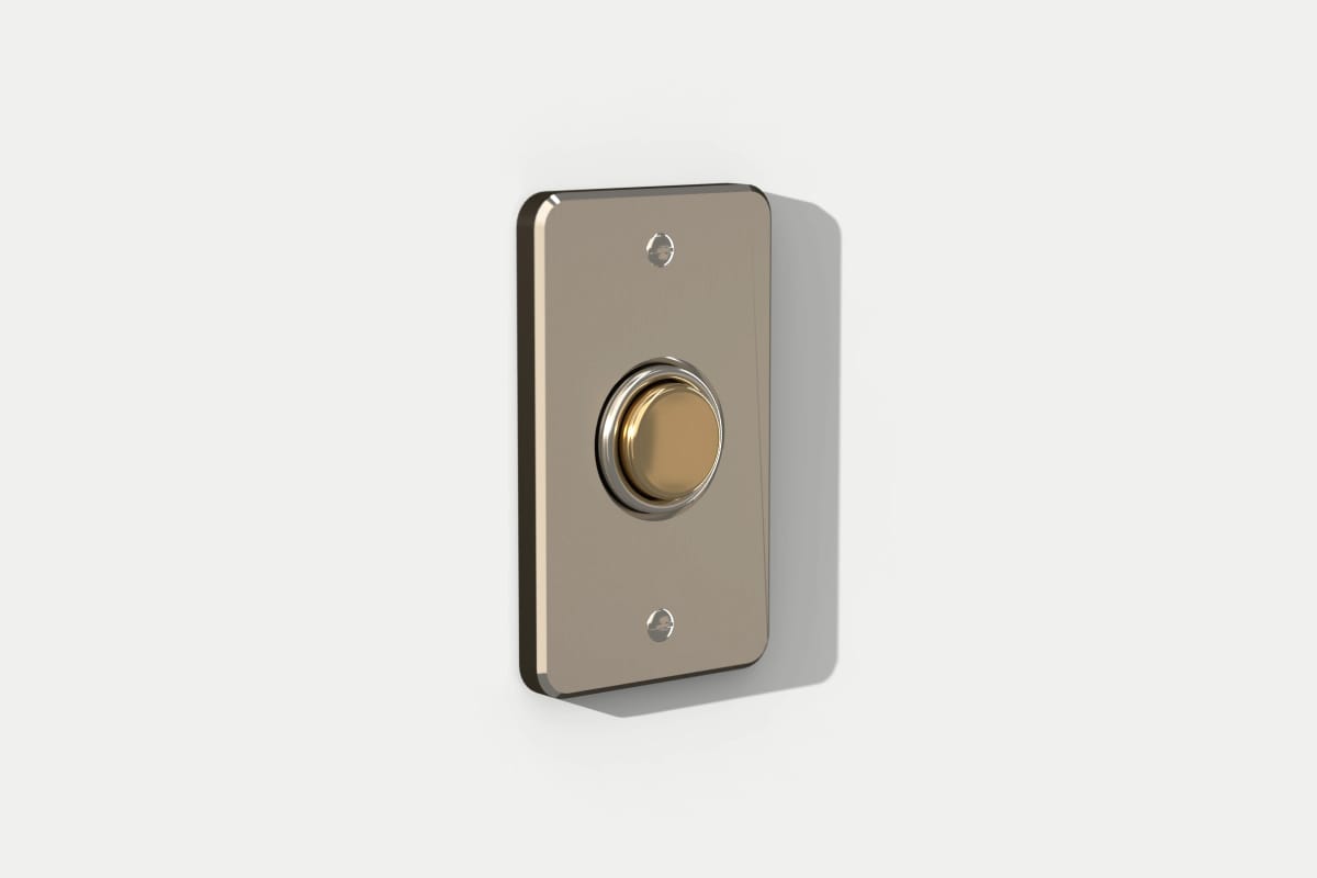 Une sonnette sur un mur clair : une platine métallique, un bouton couleur laiton