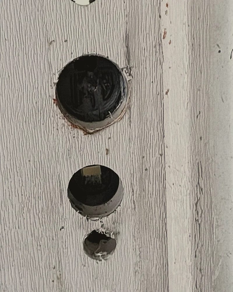 Tranche d’une porte blanche percée aux emplacements d’une serrure déposée.